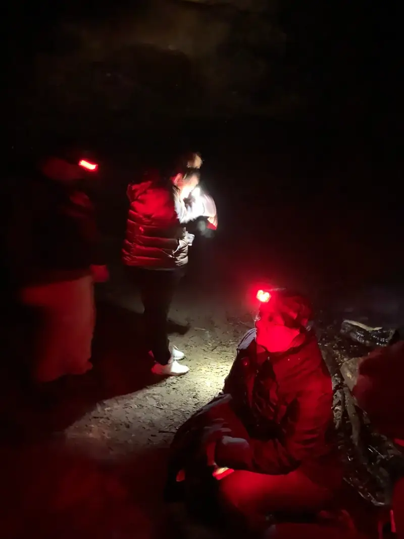 Guided group exploring a dark rocky passage