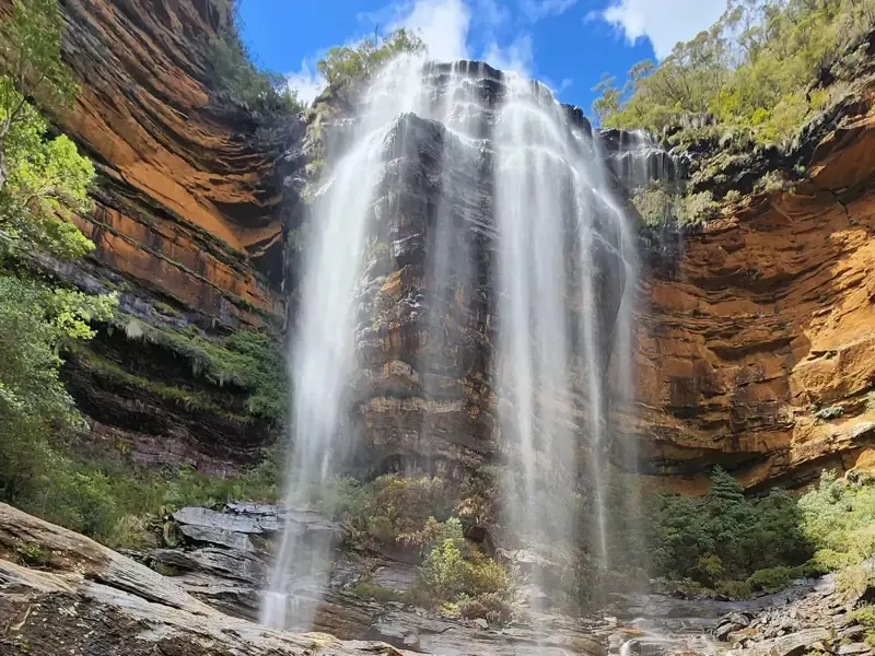 Waterfall plunging beside sandstone cliffs