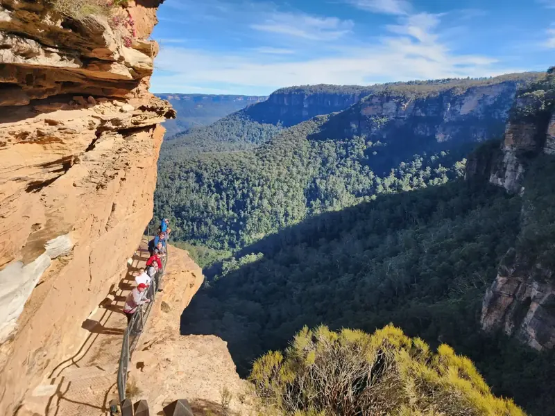 Walkers on a path beneath a sandstone overhang