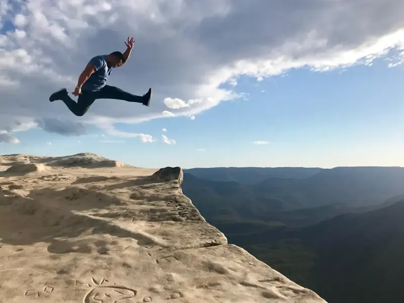 Visitor jumping above a rocky viewpoint — historical listing photo